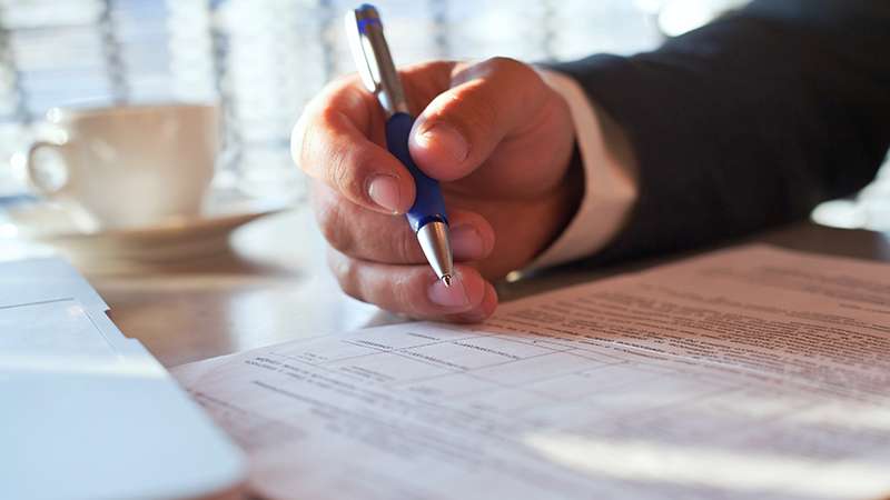 Man holding a pen, on a table